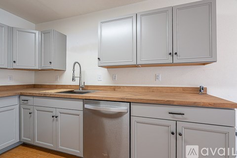 A kitchen with grey cabinets and a wooden countertop.