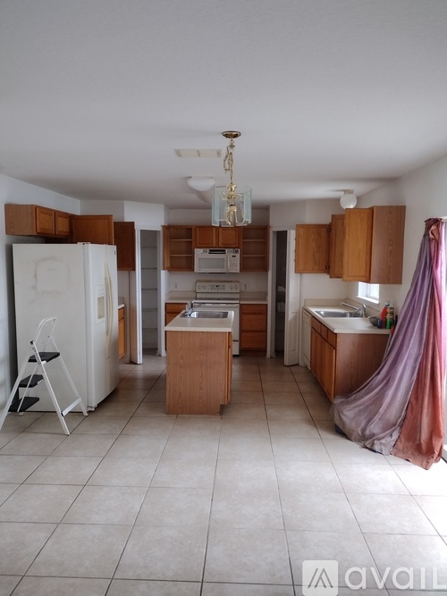 A kitchen with a white fridge, wooden cabinets, and a white ceiling.