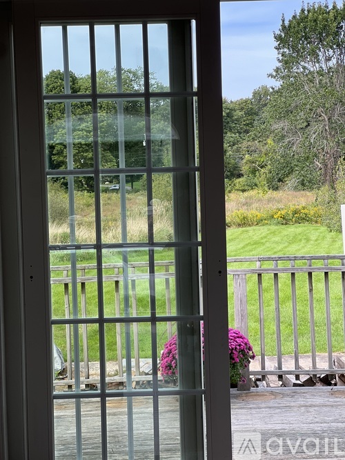 A glass door with a view of a green lawn and trees.