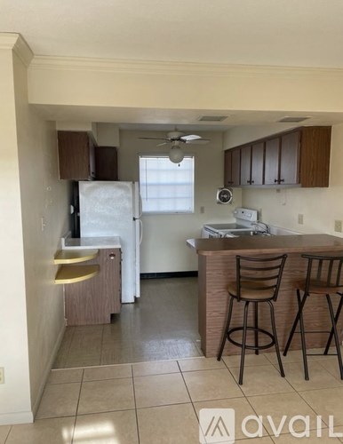 A kitchen with a refrigerator, stove, and bar stools.