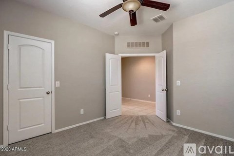 A room with a ceiling fan and two doors, one of which is open.