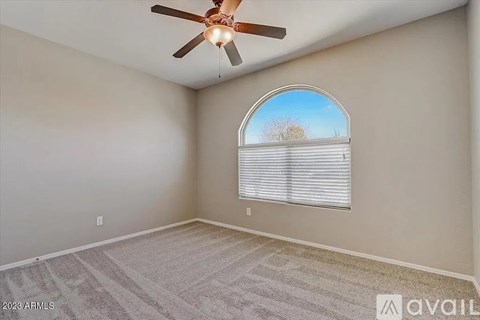 A room with a ceiling fan and a window with blinds.