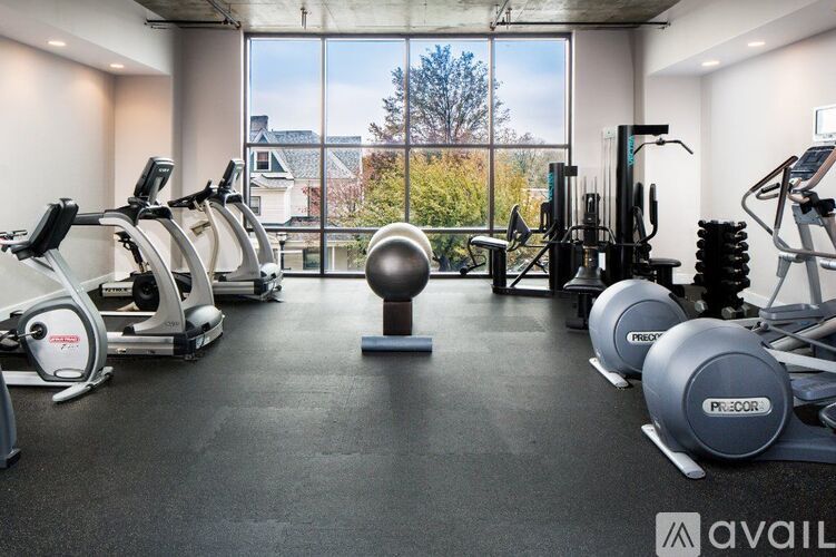 A gym with a view of trees and houses outside the window.
