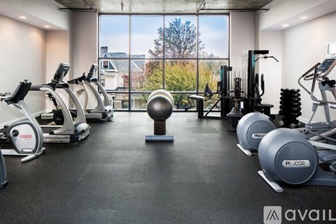 A gym with a view of trees and houses outside the window.
