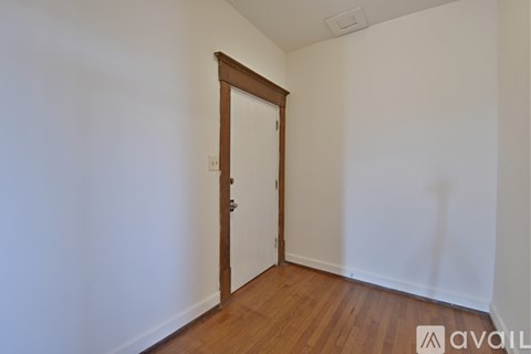 A room with a wooden door and a white wall.