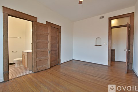 A room with wooden floors and a bathroom with a toilet and sink.