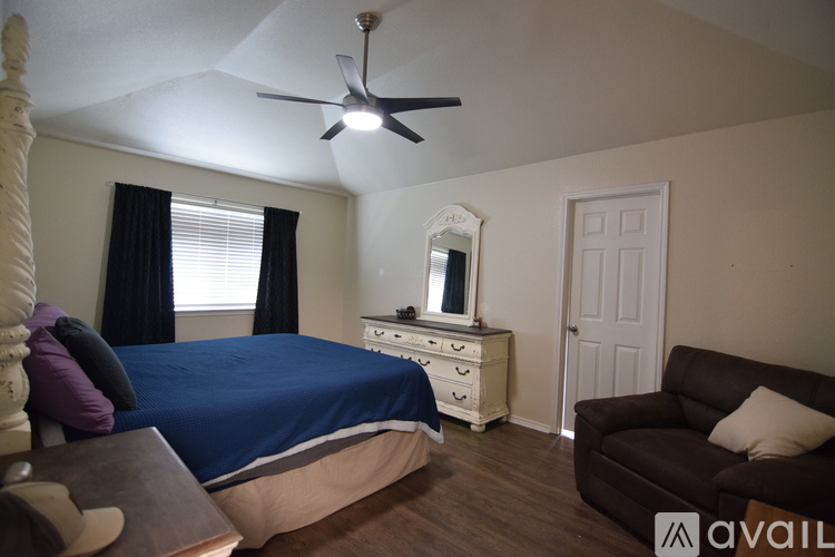 A bedroom with a bed, dresser, and couch.