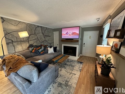 A living room with a grey couch and a TV mounted on the wall.