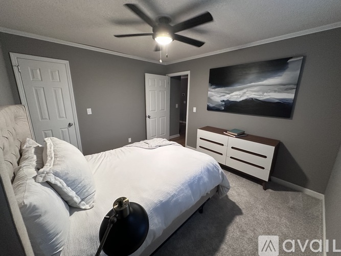 A bedroom with a white bed and a ceiling fan.