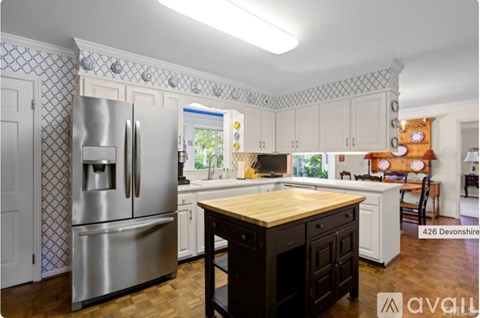 A kitchen with a wooden table and a stainless steel refrigerator.