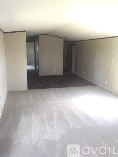 A room with a white floor and walls, and a door in the background.
