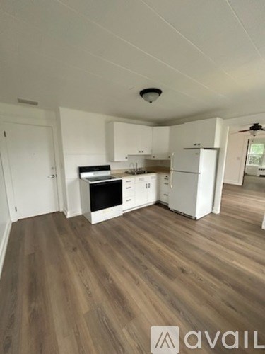 A kitchen with white cabinets and a wooden floor.
