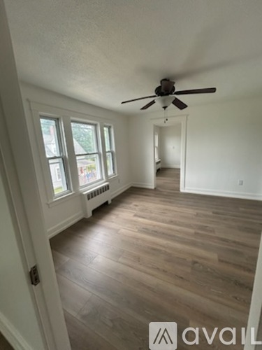 A room with a ceiling fan and wooden floors.