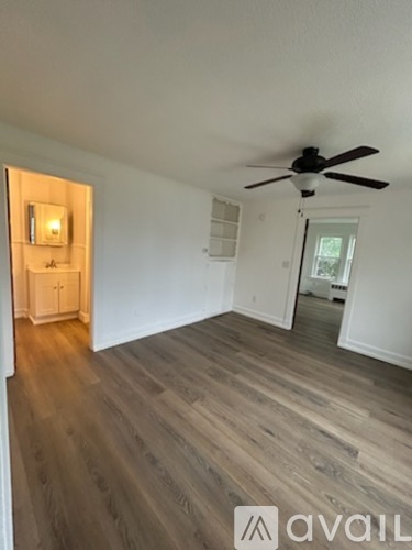A room with a ceiling fan and wooden flooring.