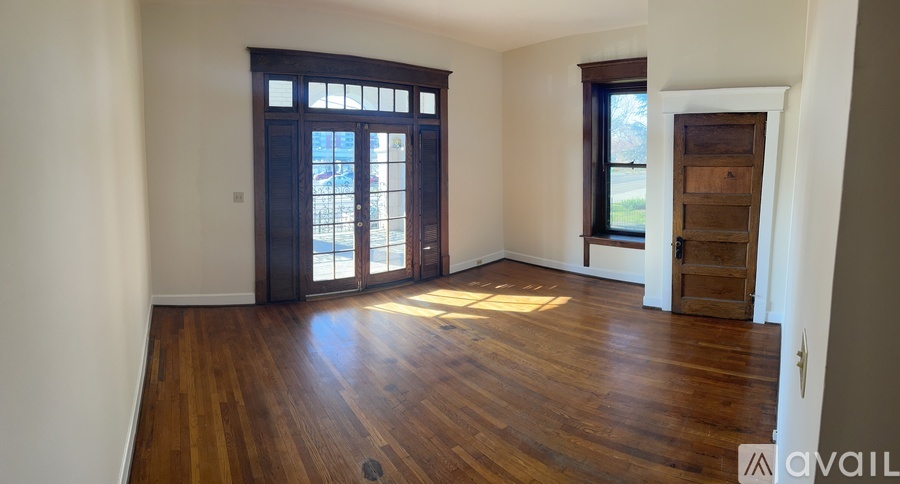A room with wooden floors and a large window with a view of the outside.