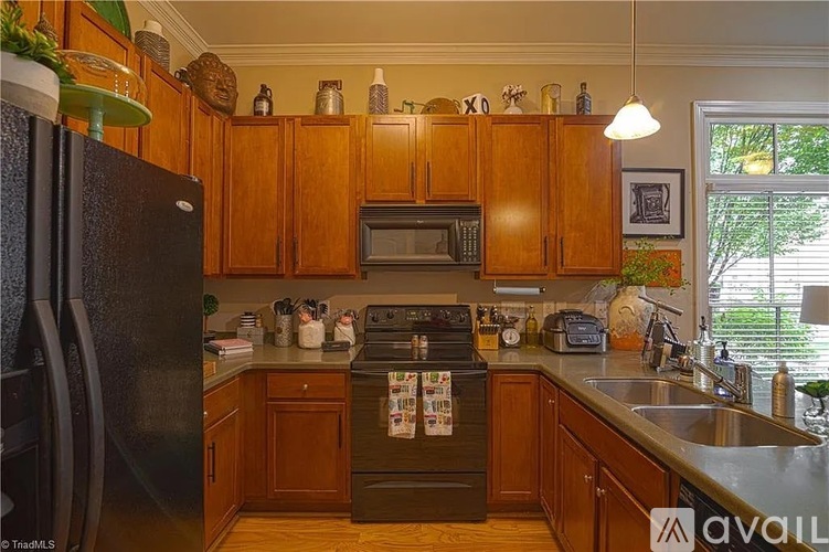 A kitchen with wooden cabinets and a black fridge.