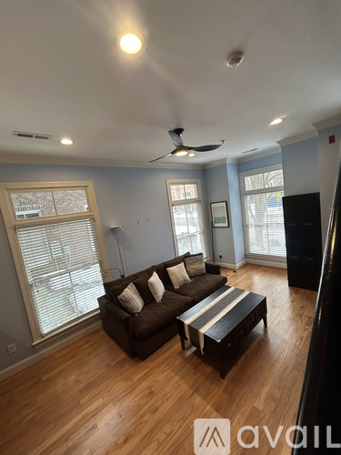 A living room with a brown couch and a ceiling fan.