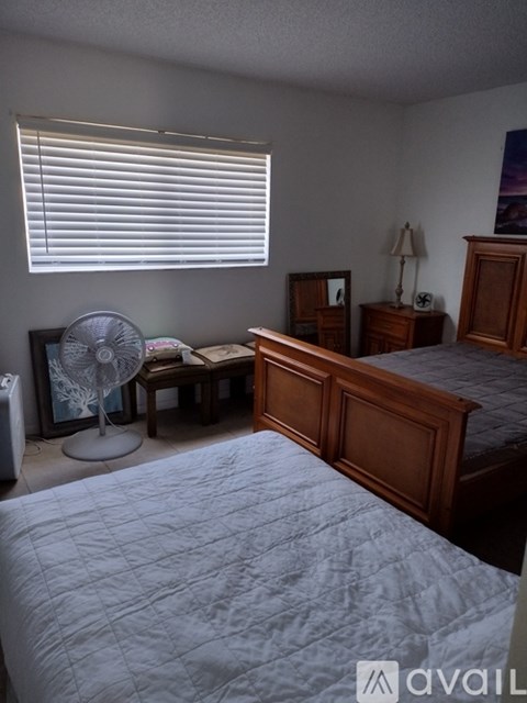 A bedroom with a bed, dresser, and fan.