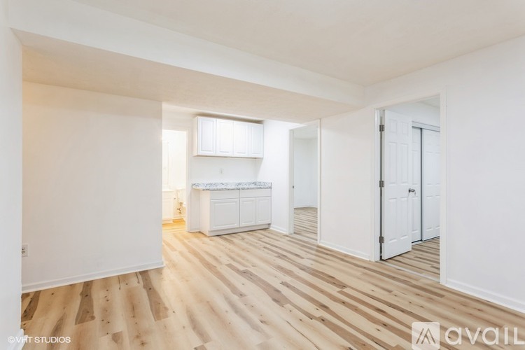 A spacious room with wooden flooring and white walls.