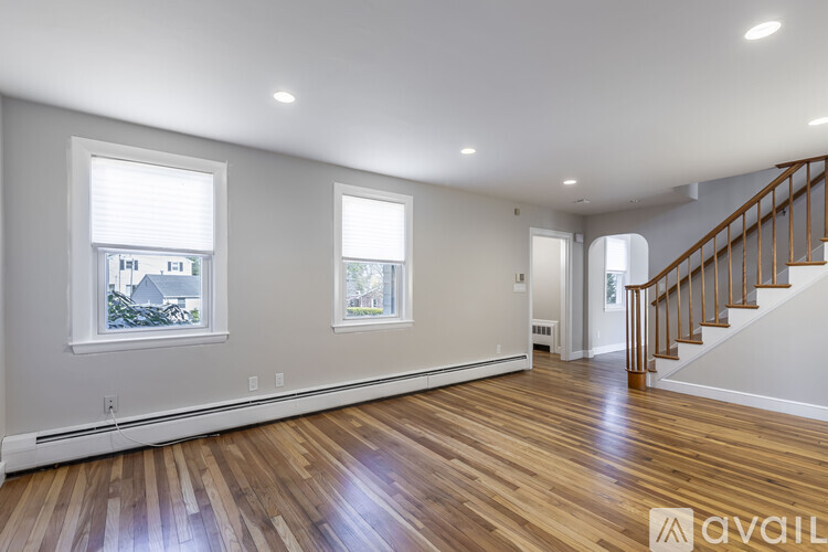 A spacious room with wooden floors and a staircase.