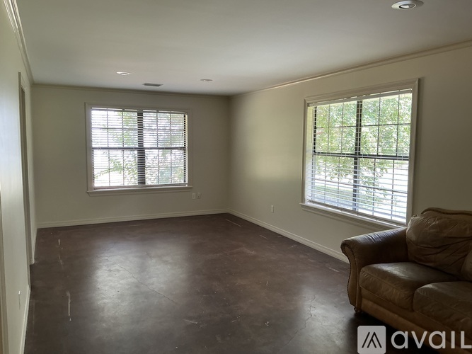 A living room with a couch and two windows.
