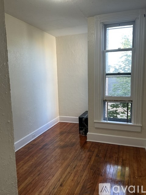 A room with a window and wooden floors is available.