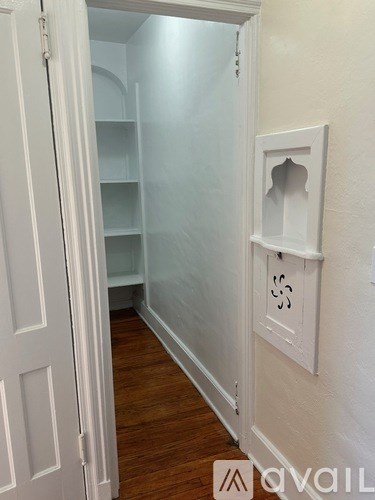 A white door with a glass panel and a white shelf bracket on the wall.