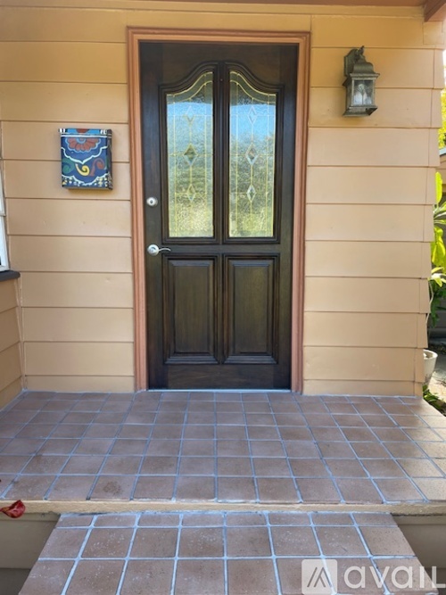 A black door with a glass window is set in a beige wall.