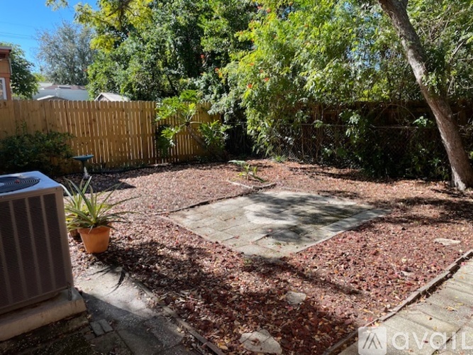 A backyard with a red brick patio and a wooden fence.