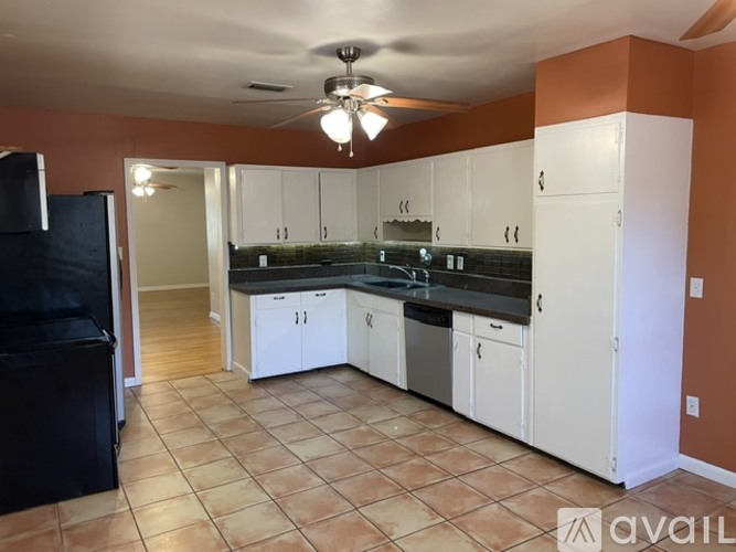 A kitchen with white cabinets and a black fridge.