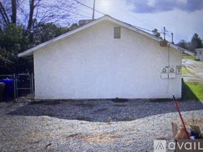 A white building with a gravel area in front.