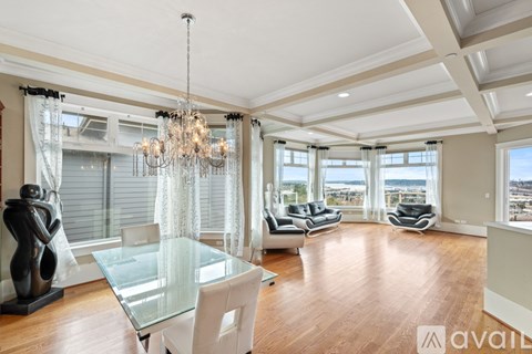 A spacious living room with a glass table and a chandelier.
