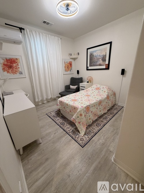 A bedroom with a floral bedspread and a framed picture on the wall.