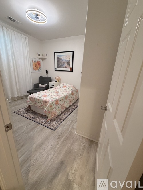 A bedroom with a bed, chair, and painting on the wall.