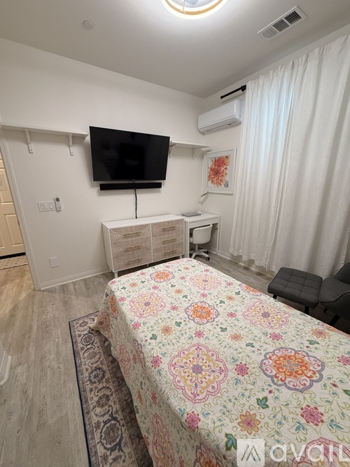A bedroom with a floral bedspread and a flat screen TV mounted on the wall.