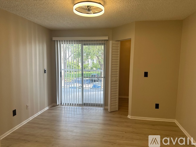 A spacious room with a sliding glass door leading to a balcony.