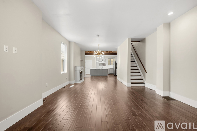 A spacious room with wooden floors and a staircase leading to the upper level.