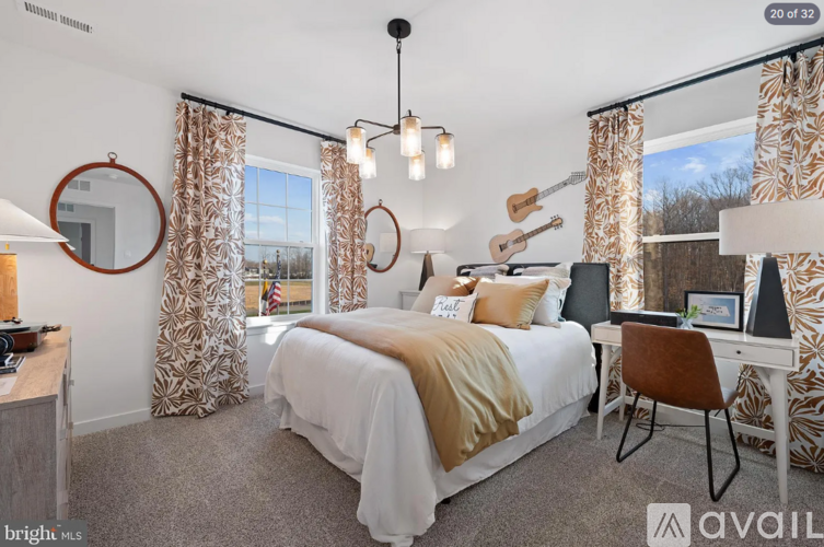 A bedroom with a large bed, a desk with a chair, and a guitar hanging on the wall.