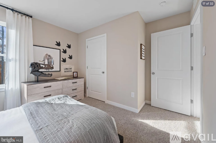 A bedroom with a bed, dresser, and two doors.