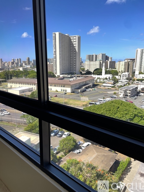 A cityscape is visible through a window with a view of a parking lot and buildings.
