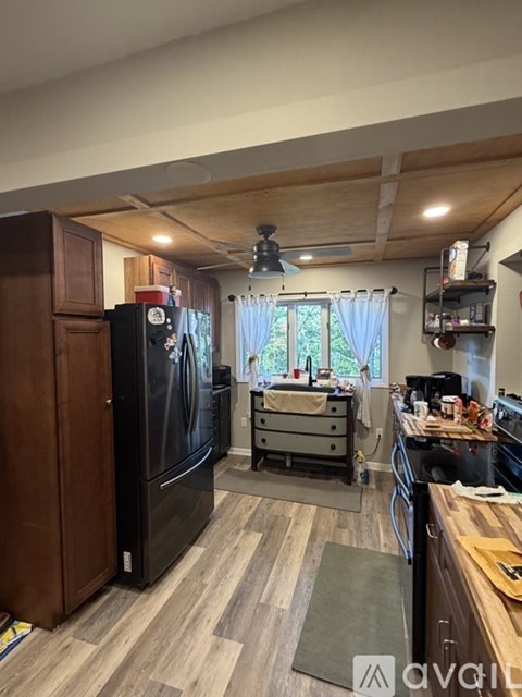 A kitchen with a black fridge and wooden floors.