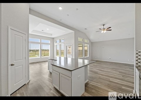 A spacious kitchen with a large island and a ceiling fan.
