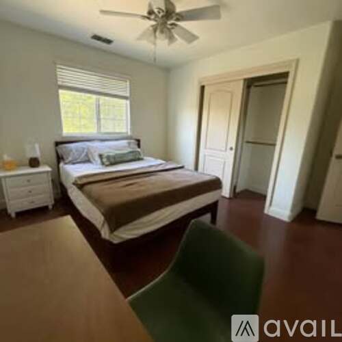 A bedroom with a bed, nightstand, and chair.