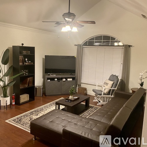 A living room with a black leather couch and a television.