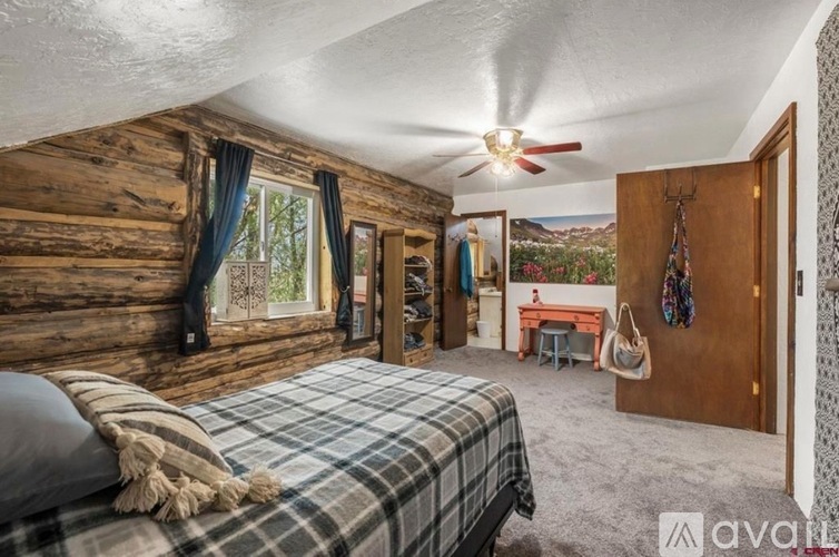 A bedroom with a bed, a desk, and a ceiling fan.