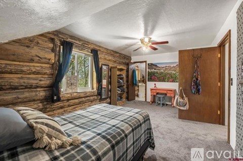 A bedroom with a bed, a desk, and a ceiling fan.