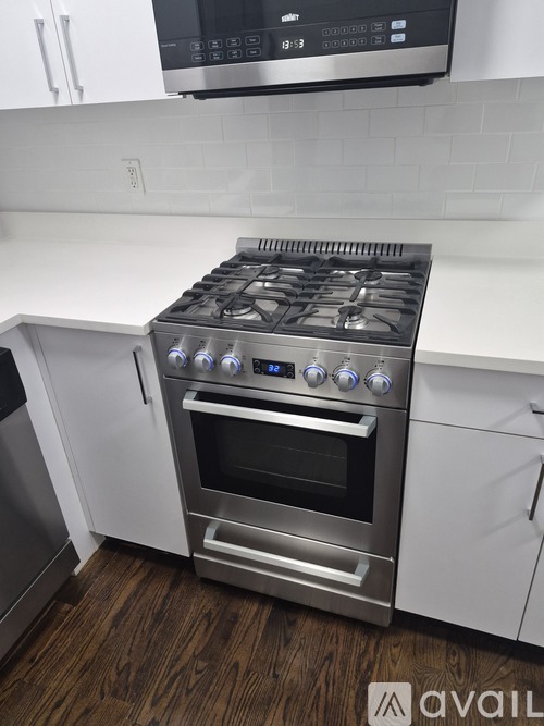 A modern kitchen with a stainless steel gas stove and white cabinets.