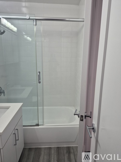 A bathroom with a glass shower door and a white bathtub.