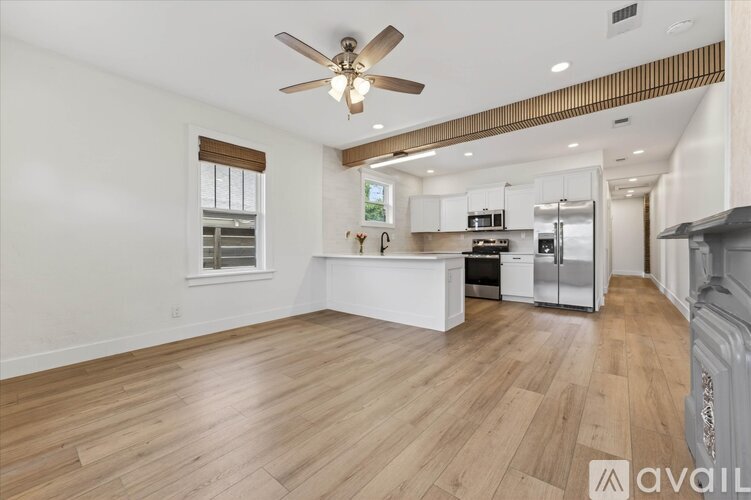 A spacious kitchen with white cabinets and a wooden floor.