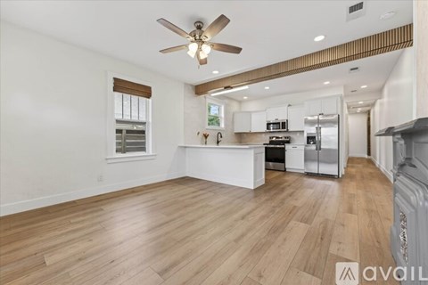 A spacious kitchen with white cabinets and a wooden floor.
